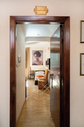 A hallway leading to a bedroom with a bed, a chair, and a painting on the wall. - Residenza delle Arti (Rome)