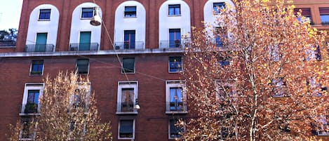 A multi-story building with a brick facade, multiple windows, and balconies.