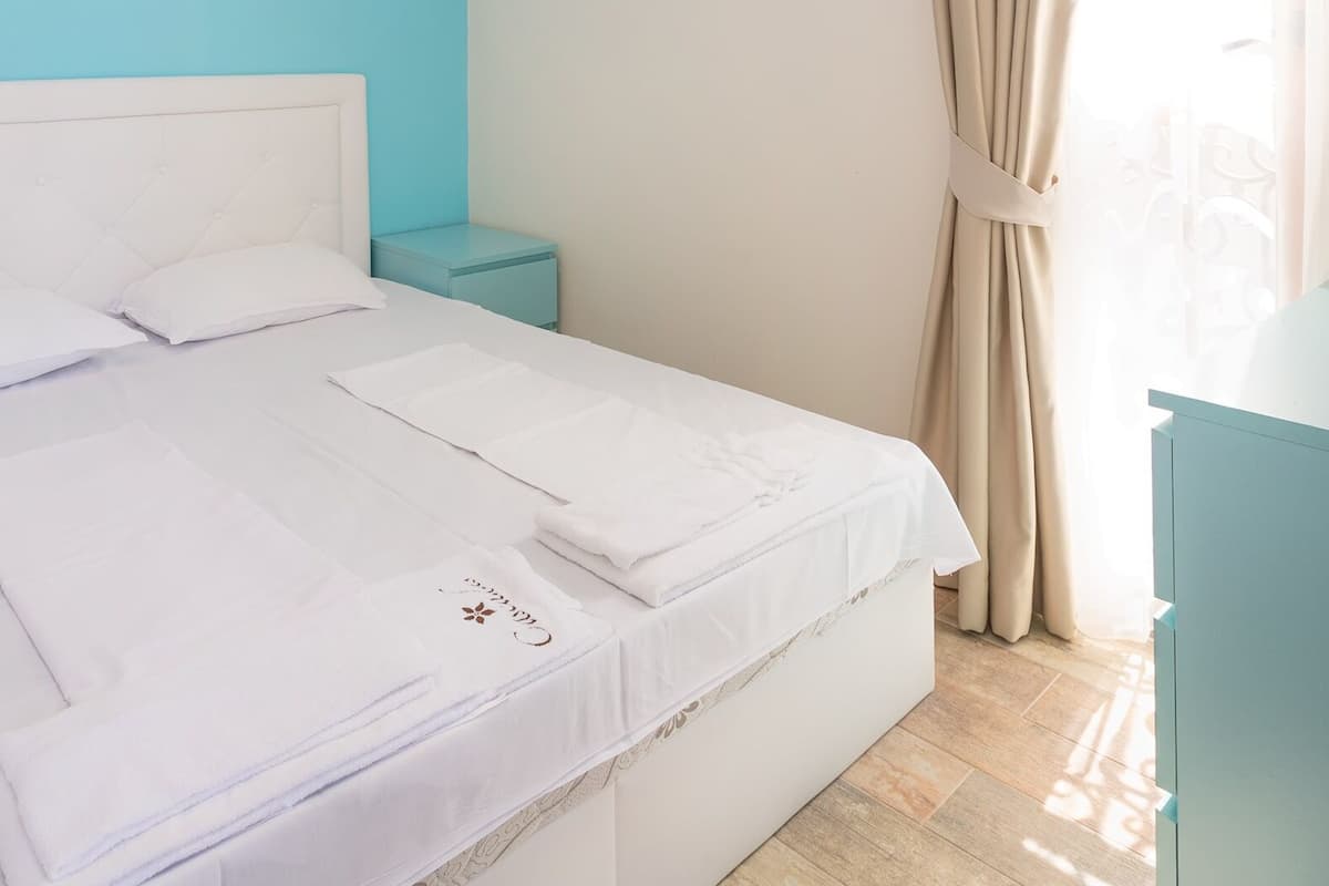 A neatly made bed with white linens and a decorative pillow.