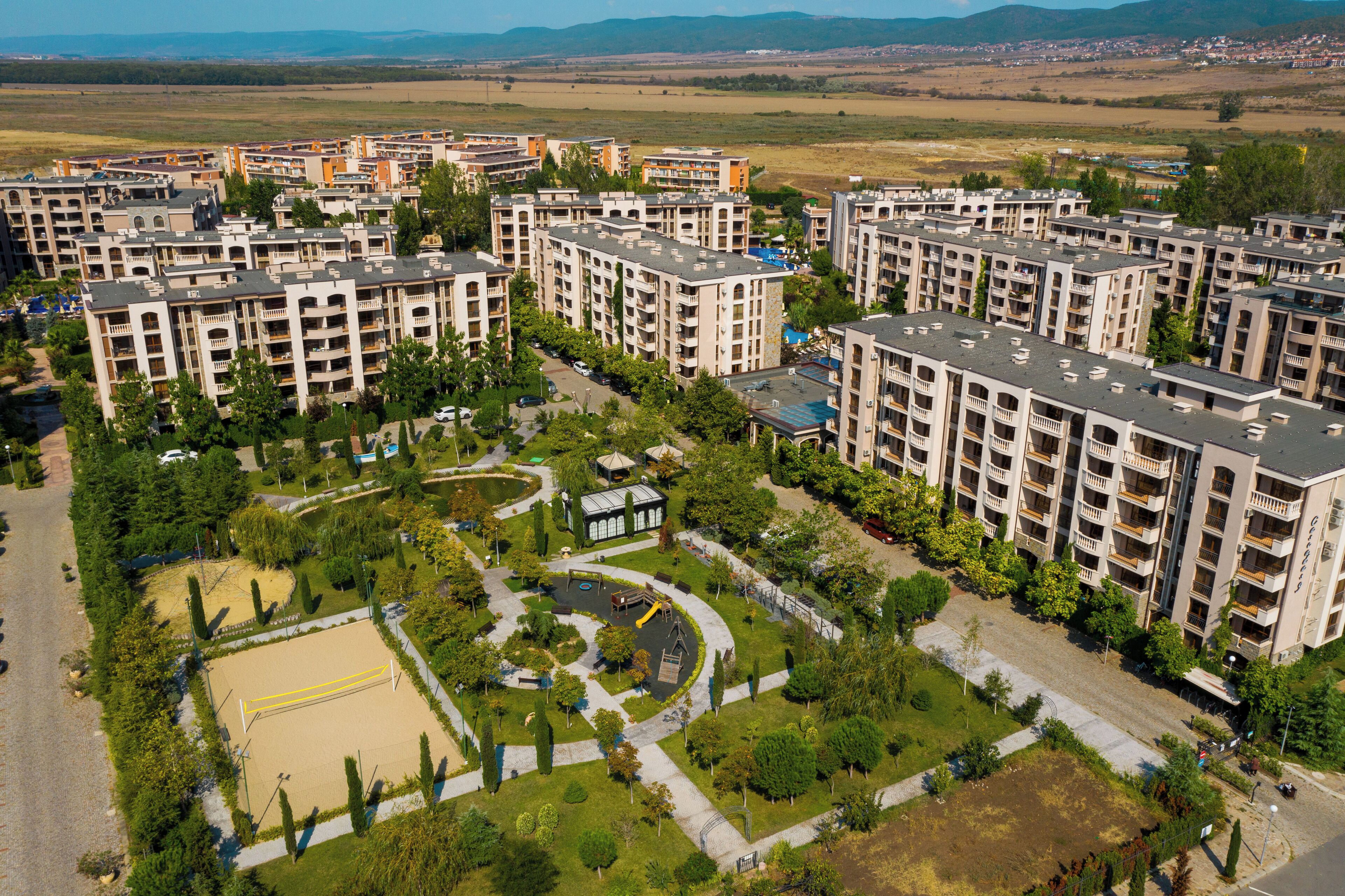 Un complex residencial amb diversos edificis d'apartaments, un parc central amb zones de jocs i un camp esportiu.