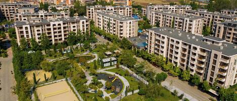 Un complex residencial amb diversos edificis d'apartaments, un parc central amb zones de jocs i un camp esportiu.