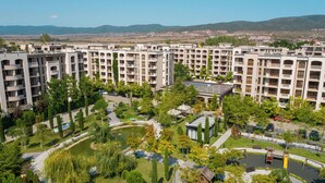 Een wooncomplex met meerdere appartementengebouwen, aangelegde tuinen en een speelplaats.