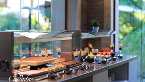 A buffet counter with various desserts and drinks, a glass display case, and a view of greenery outside. - Cascadas Family Resort (Sunny Beach)