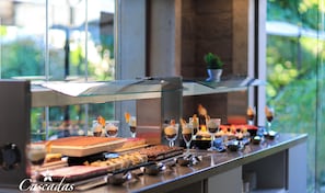 A buffet counter with various desserts and drinks, a glass display case, and a view of greenery outside. - Cascadas Family Resort (Sunny Beach)