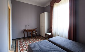 A hotel room with two beds, a desk, a chair, a wardrobe, and a patterned floor. - Bed & Breakfast Ekoliving (Milan)
