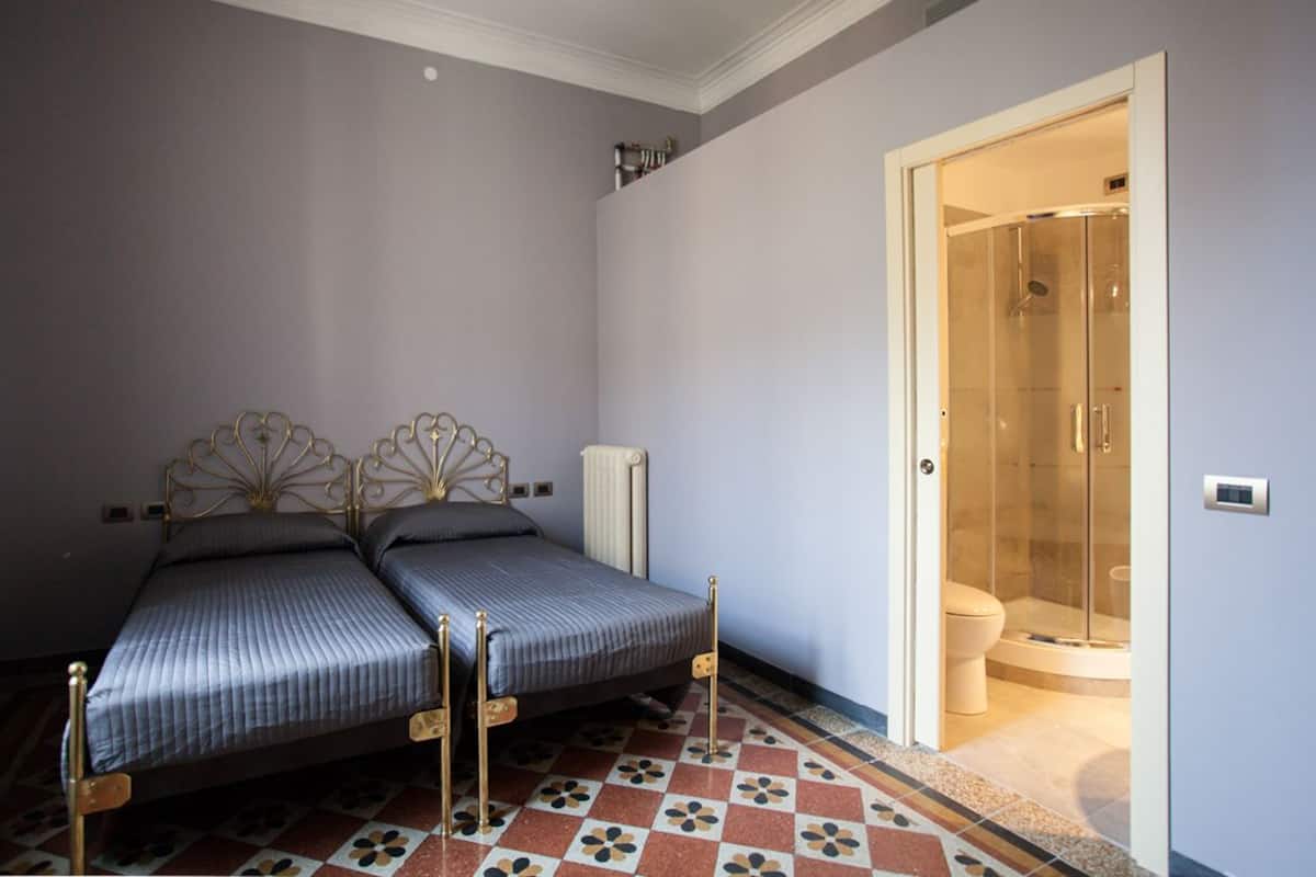 Un dormitorio con dos camas, ducha y suelo de baldosas.