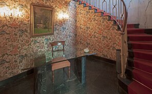 A room with a glass table, a chair, a painting, and a staircase with red steps. - Bed & Breakfast Ekoliving (Milan)