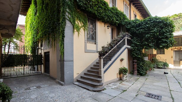 Un patio con una escalera de piedra que conduce a un edificio cubierto de hiedra.