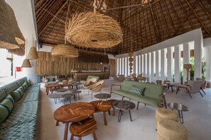 A spacious indoor area with a high ceiling, wicker furniture, and a green sofa.