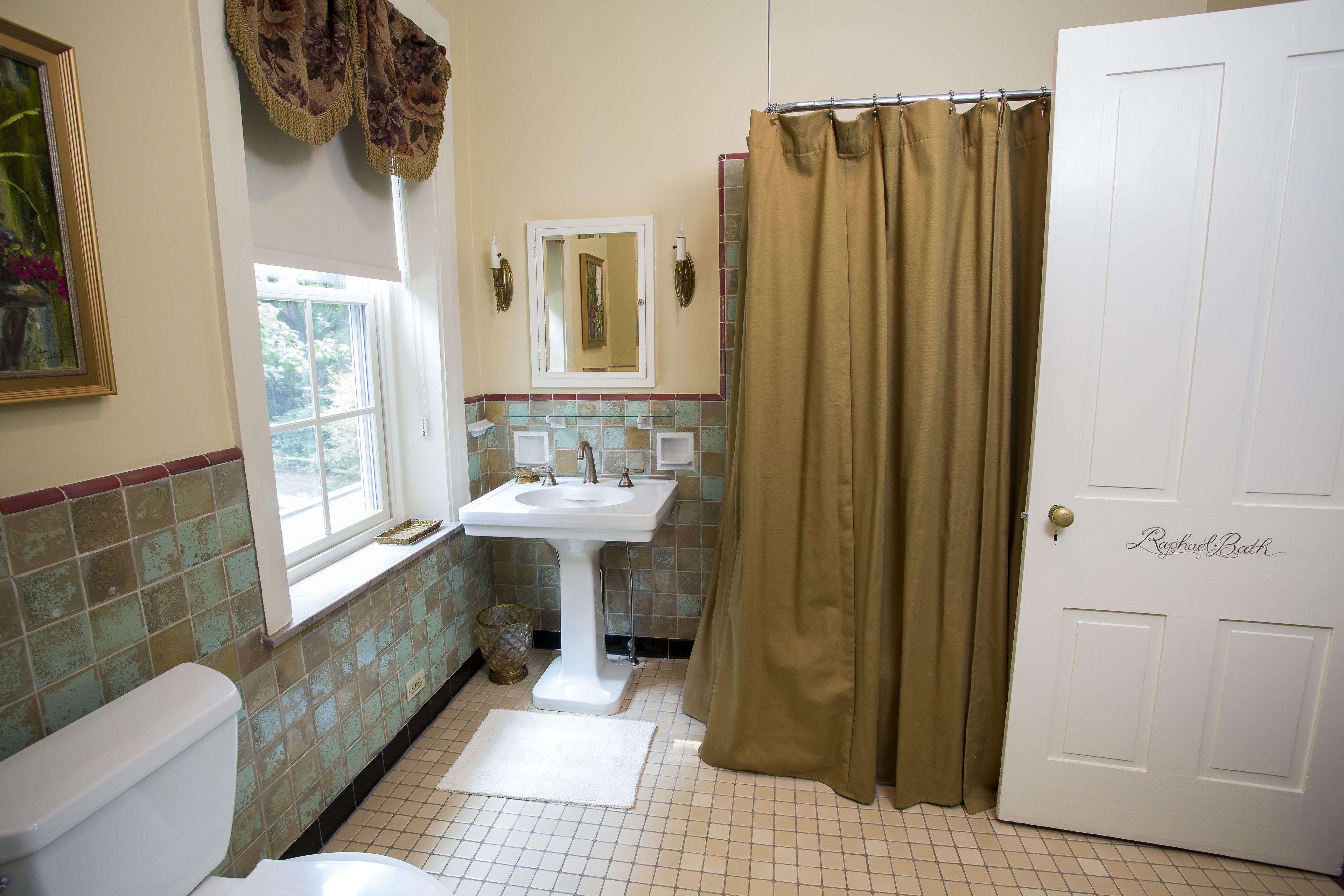 A bathroom with a white sink, a toilet, a window, and a shower curtain.