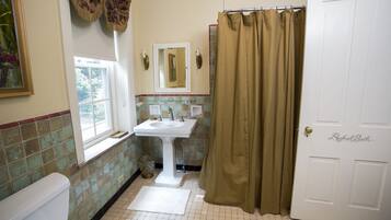 A bathroom with a white sink, a toilet, a window, and a shower curtain.