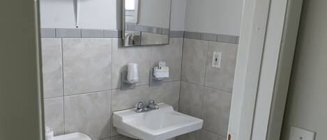 Une petite salle de bain propre, équipée de toilettes, d’un lavabo et d’un miroir.