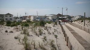 Une zone résidentielle côtière avec des maisons, une plage de sable et une promenade en bois.