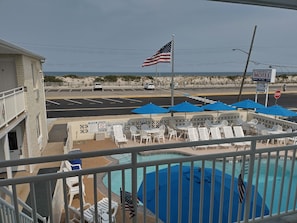 A motel with a pool area, outdoor seating, and an American flag. - Luna Mar Motel (Seaside Park)