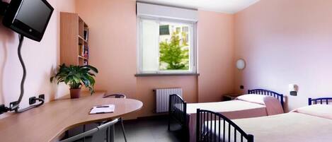 A bedroom with a desk, a television, a window, a radiator, and a bed.