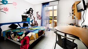 A modern bedroom with a colorful bedspread, a desk with a computer, and a view of the outdoors through a sliding door. - La Cordata Accommodation - Zumbini 6 (Milan)