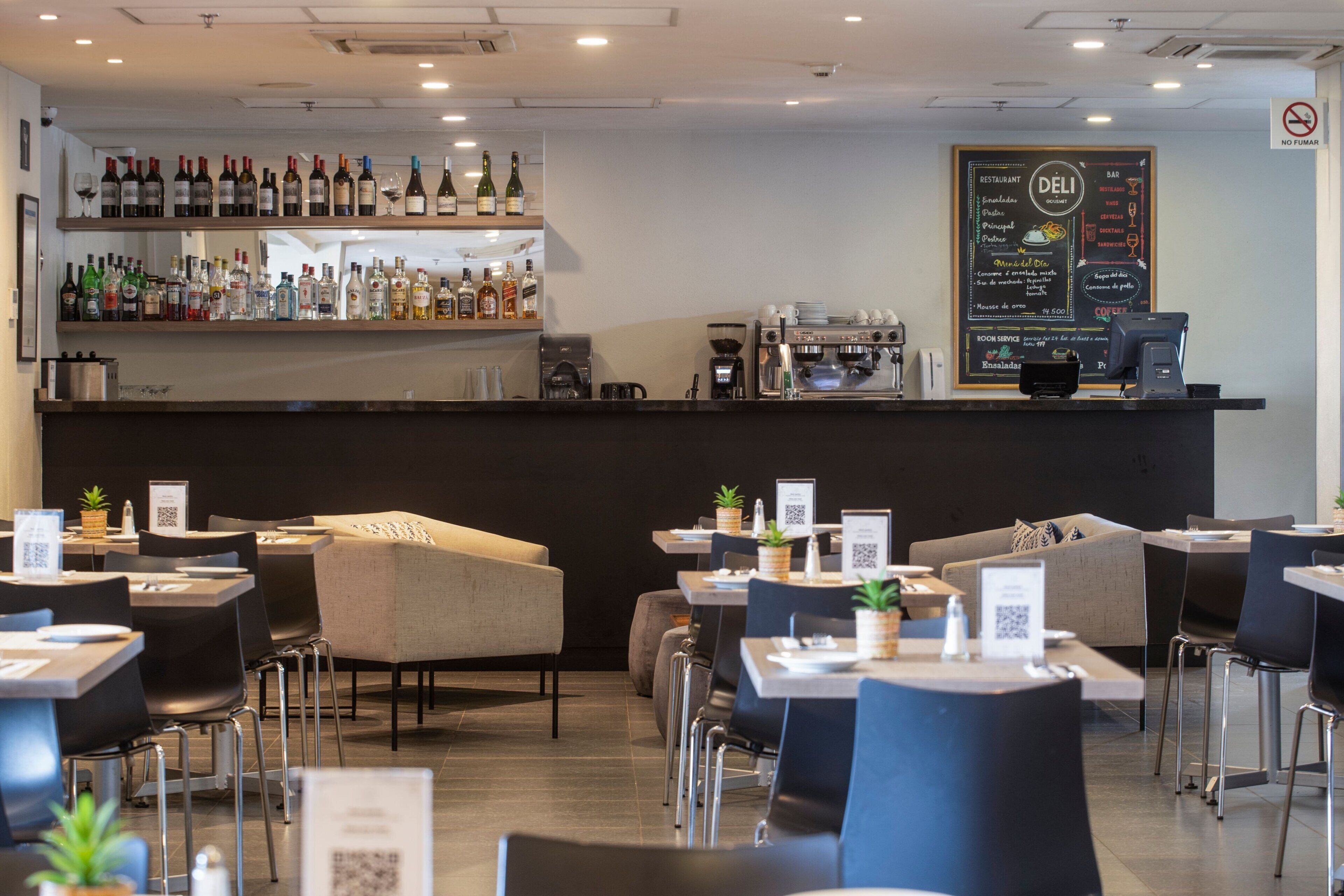 Un restaurante moderno con zona de bar, mesas y un tablero de menú.