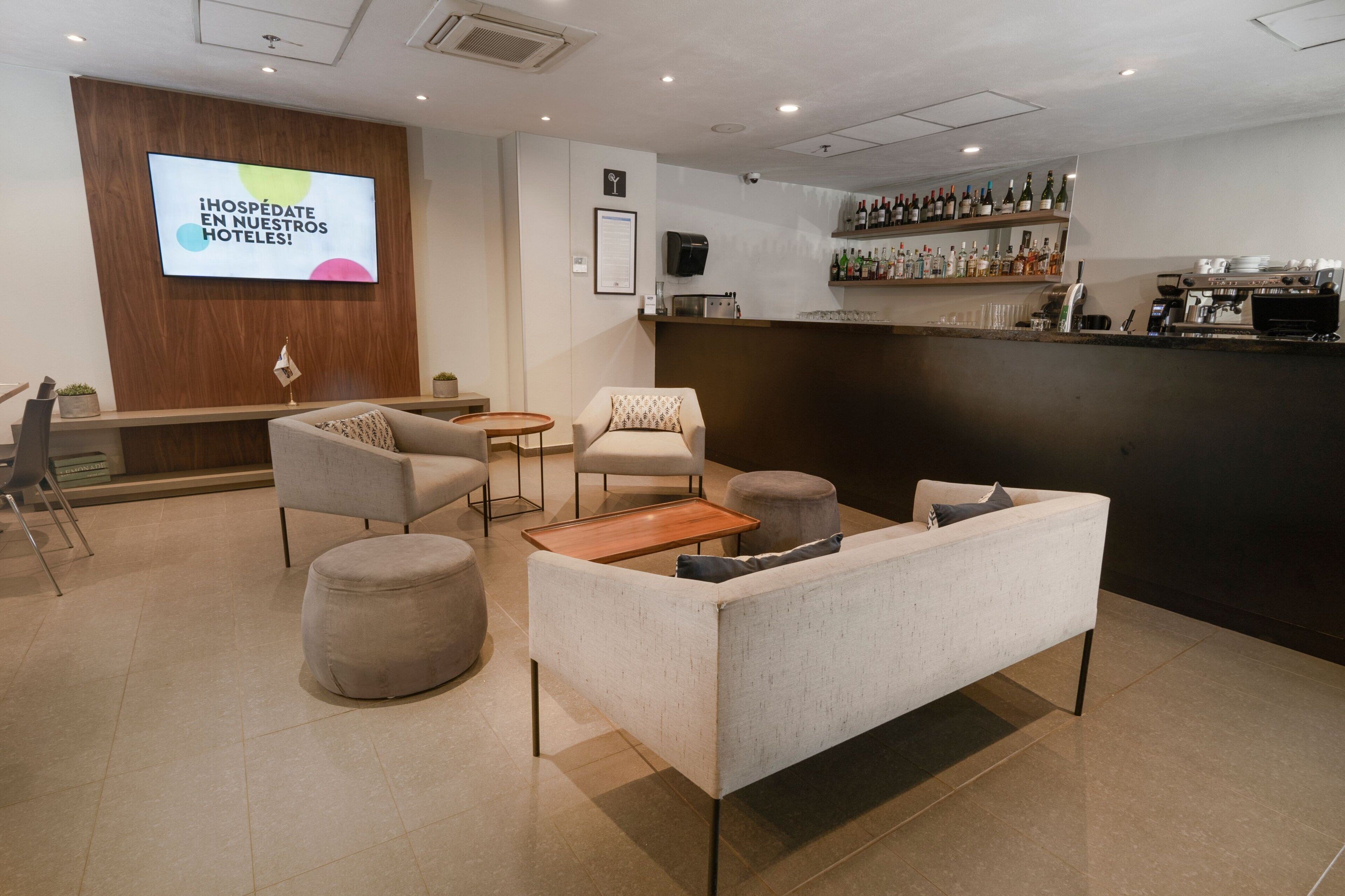 Un vestíbulo de hotel con mostrador de recepción, zona de estar y bar.