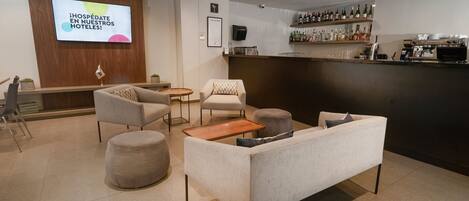 Un vestíbulo de hotel con mostrador de recepción, zona de estar y bar.