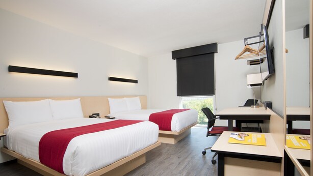 Een hotelkamer met twee bedden, een bureau en een stoel.