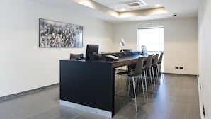 Een moderne kantoorruimte met een receptiebalie, computer en stoelen.