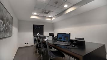 Una sala de conferencias moderna con una mesa larga, varias sillas, una computadora portátil y un proyector.