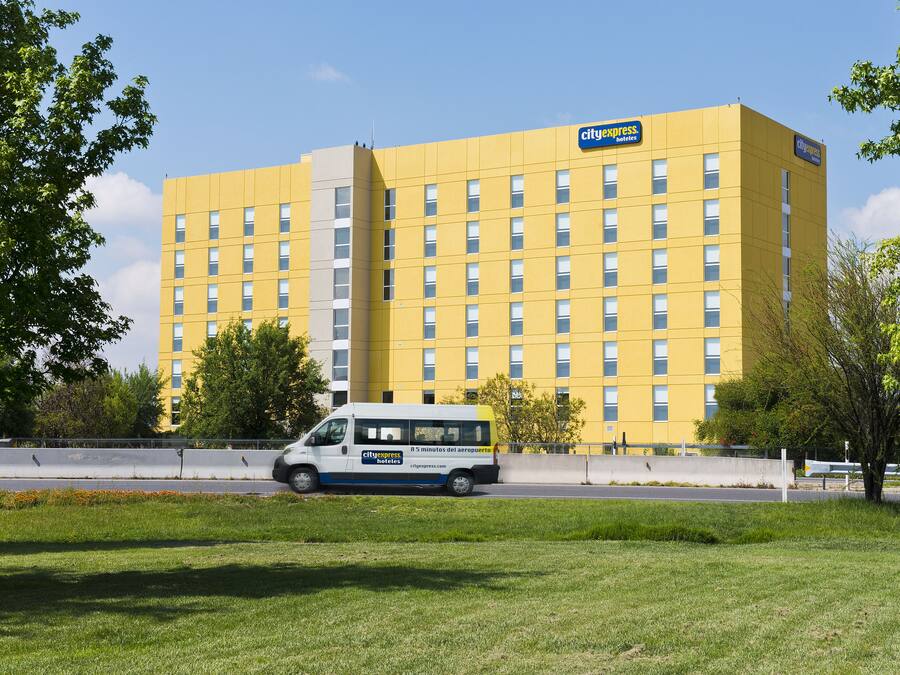 Edificio de hotel CityExpress con fachada amarilla, múltiples ventanas y una camioneta en la parte frontal.