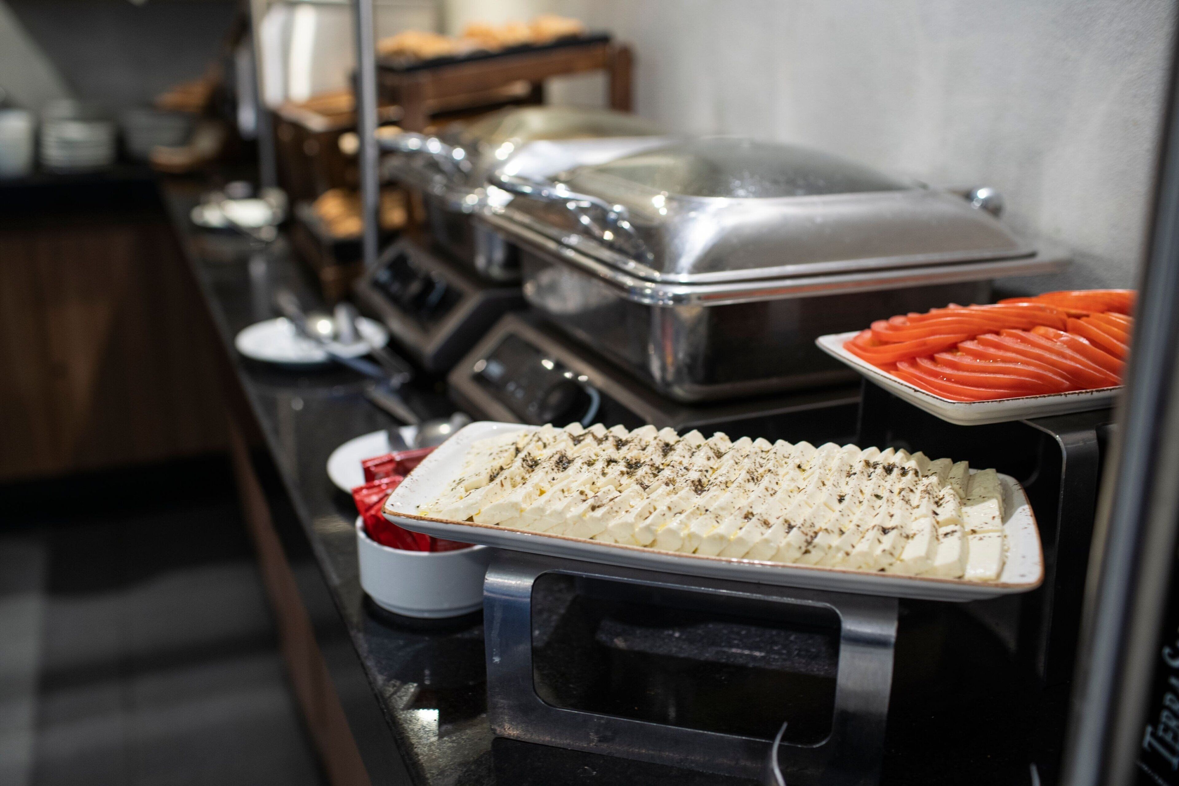 Un buffet proposant divers plats, notamment un plateau de carottes coupées en tranches et un plat contenant une substance crémeuse blanche, qui pourrait être du fromage ou une sauce.