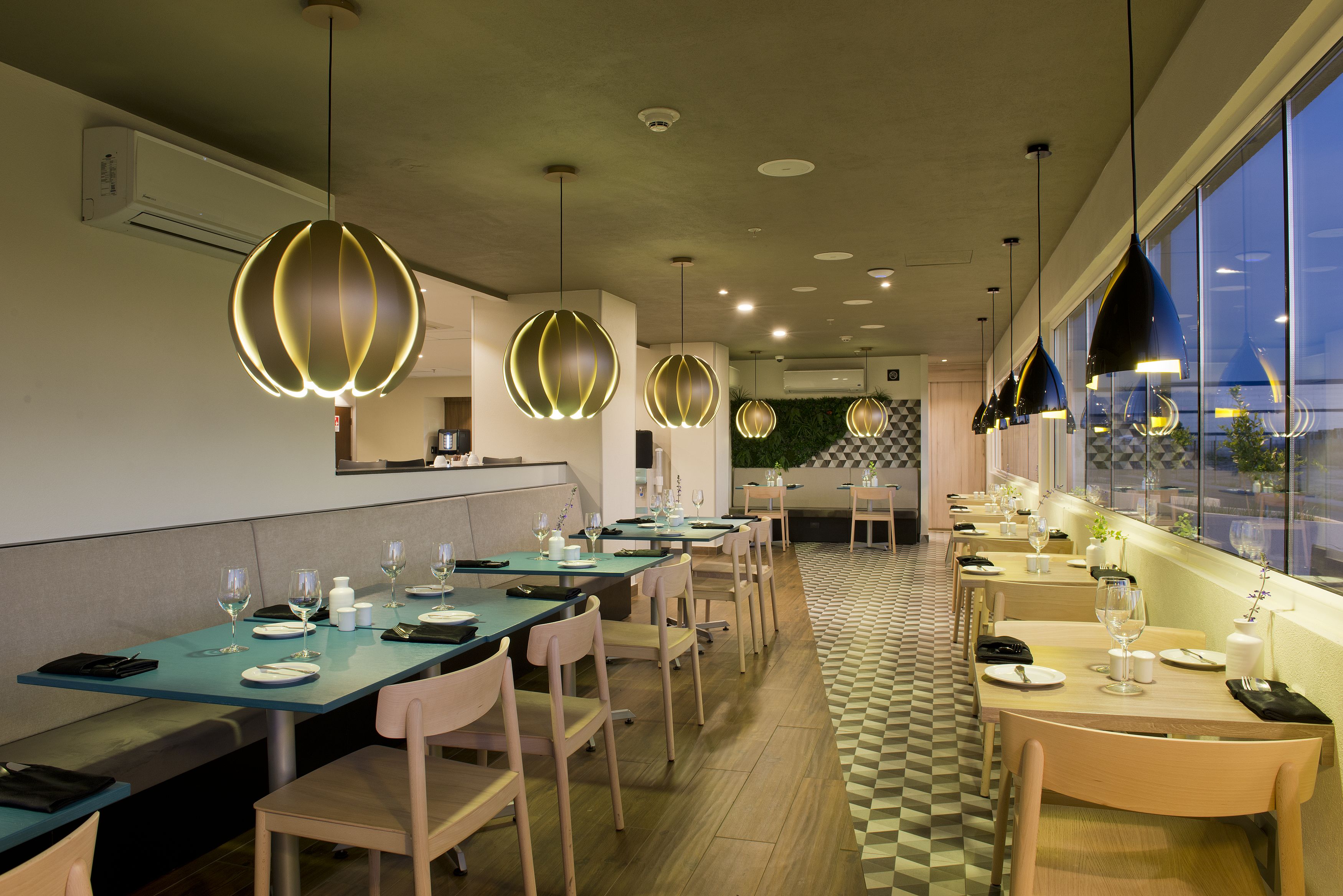 A restaurant with long tables, chairs, and pendant lighting.