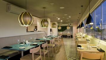 A restaurant with long tables, chairs, and pendant lighting.