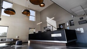 Een moderne receptiebalie met een bord, hangende lampen en een groot raam dat voor natuurlijk licht zorgt.