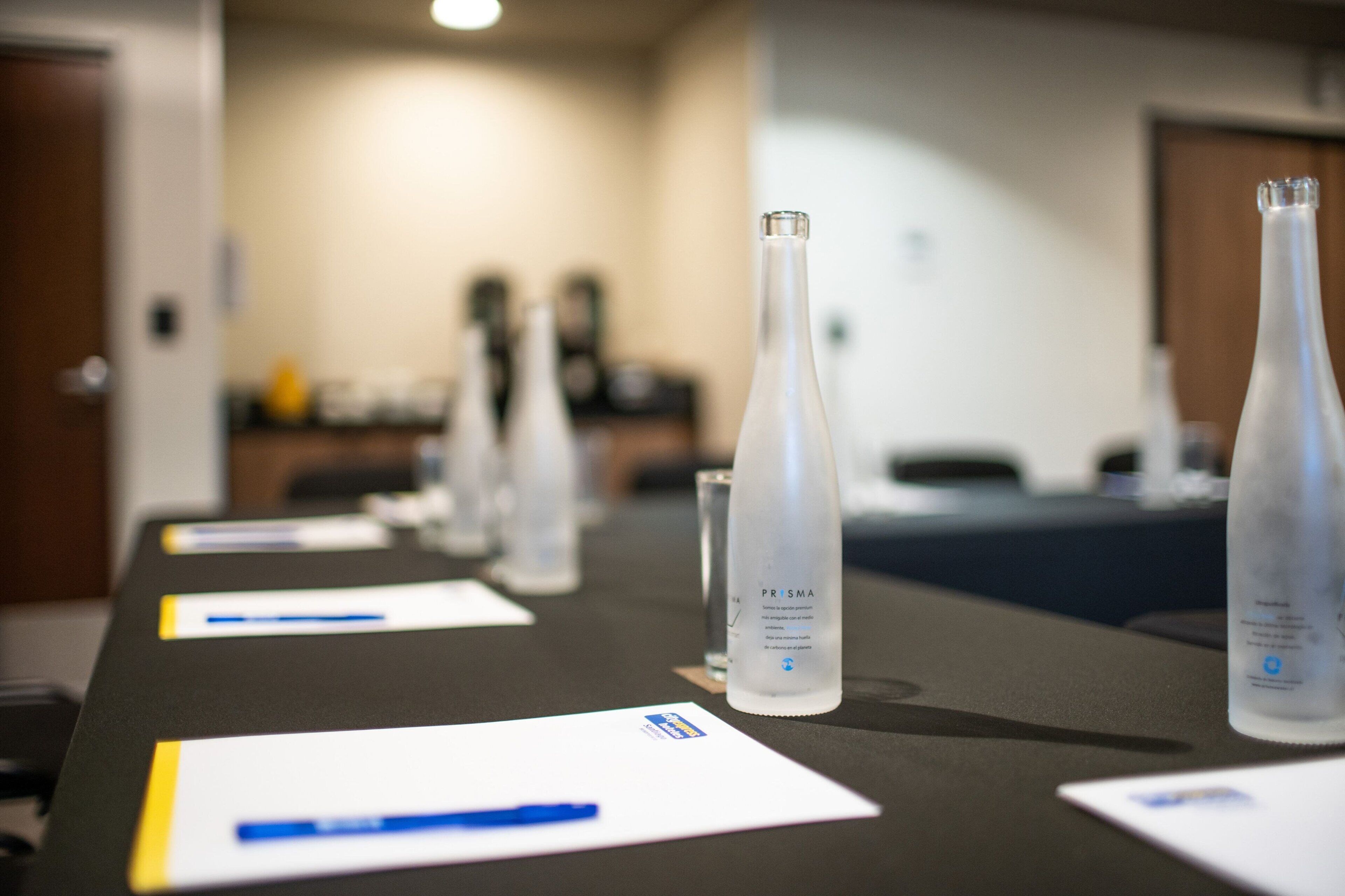A conference table with nameplates and water bottles labeled "PRISMA".