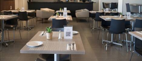 A modern restaurant with tables set for dining, a bar area in the background, and a QR code on the table.
