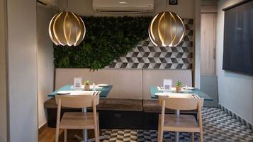 Un comedor moderno con dos mesas, sillas y una pared verde con plantas.