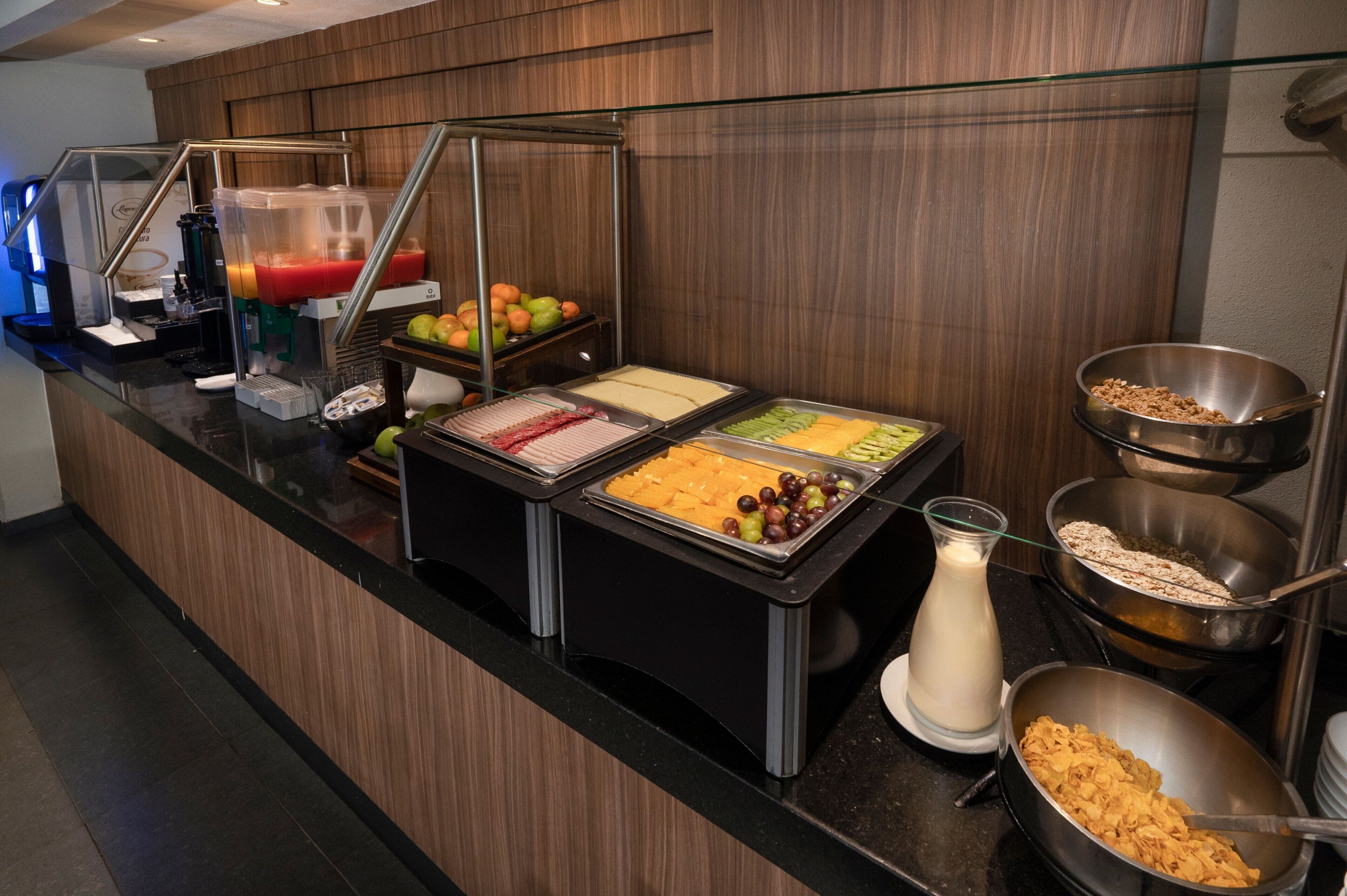 A buffet with various food options including fruits, cheeses, and cereals.
