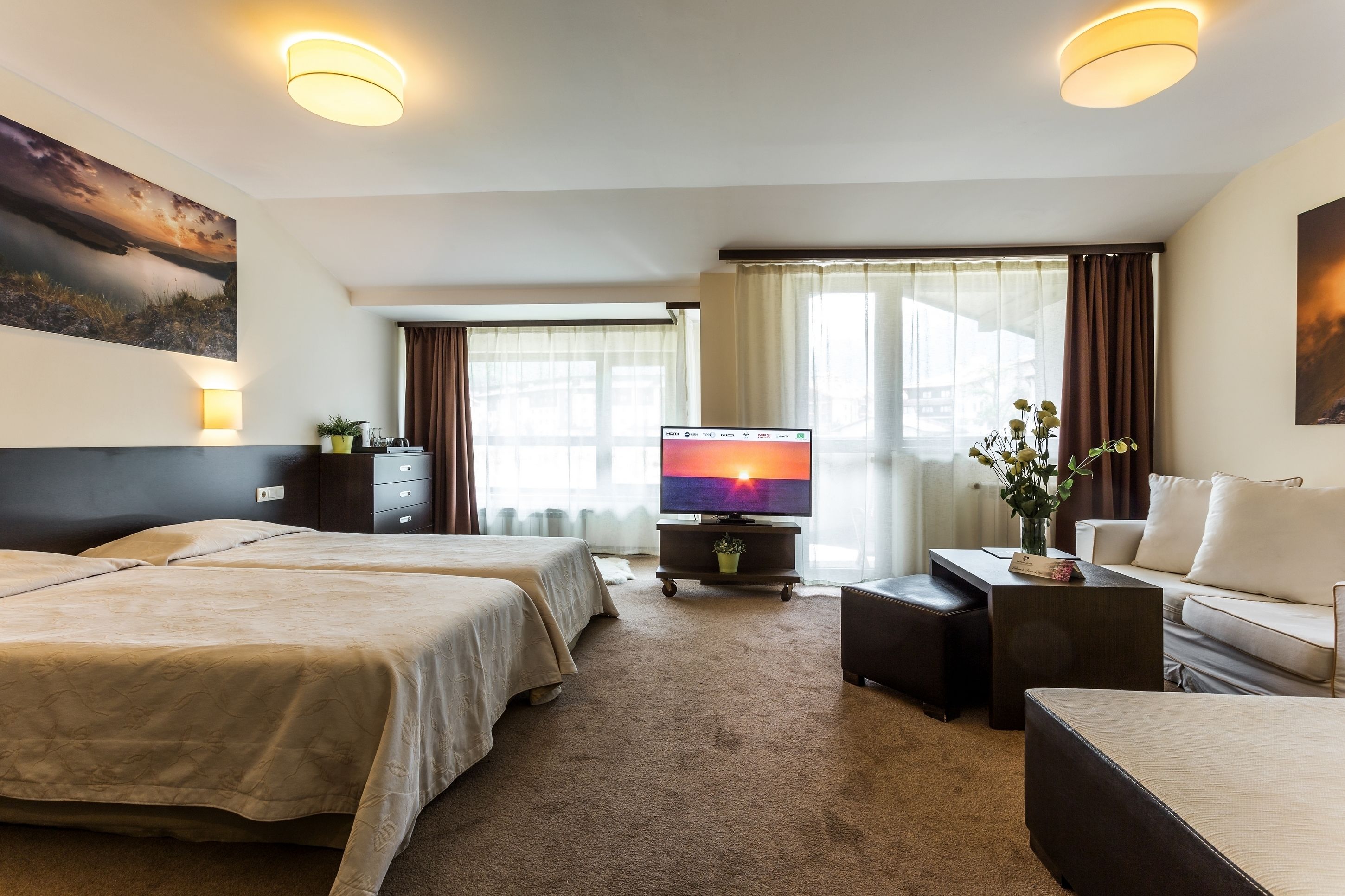 Une chambre d’hôtel avec deux lits, une télévision, un canapé et une table basse.