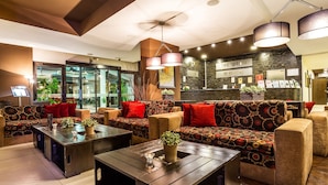 A modern hotel lobby with a reception desk, patterned sofas, and a coffee table with a plant. - Perun Lodge Hotel (Bansko)