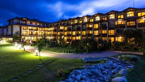 A multi-story hotel with a well-lit exterior and a landscaped garden area. - Perun Lodge Hotel (Bansko)