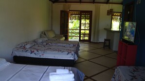 A hotel room with two beds, a TV, and a view of greenery outside. - Pousada Capitão Gancho (Maraú)