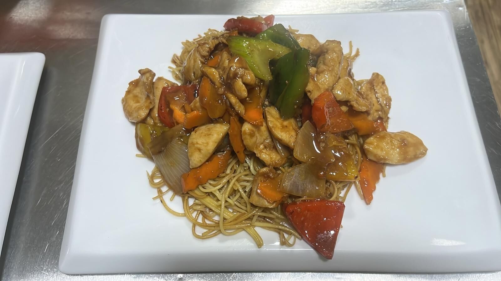 Un plato de fideos salteados con verduras y pollo.