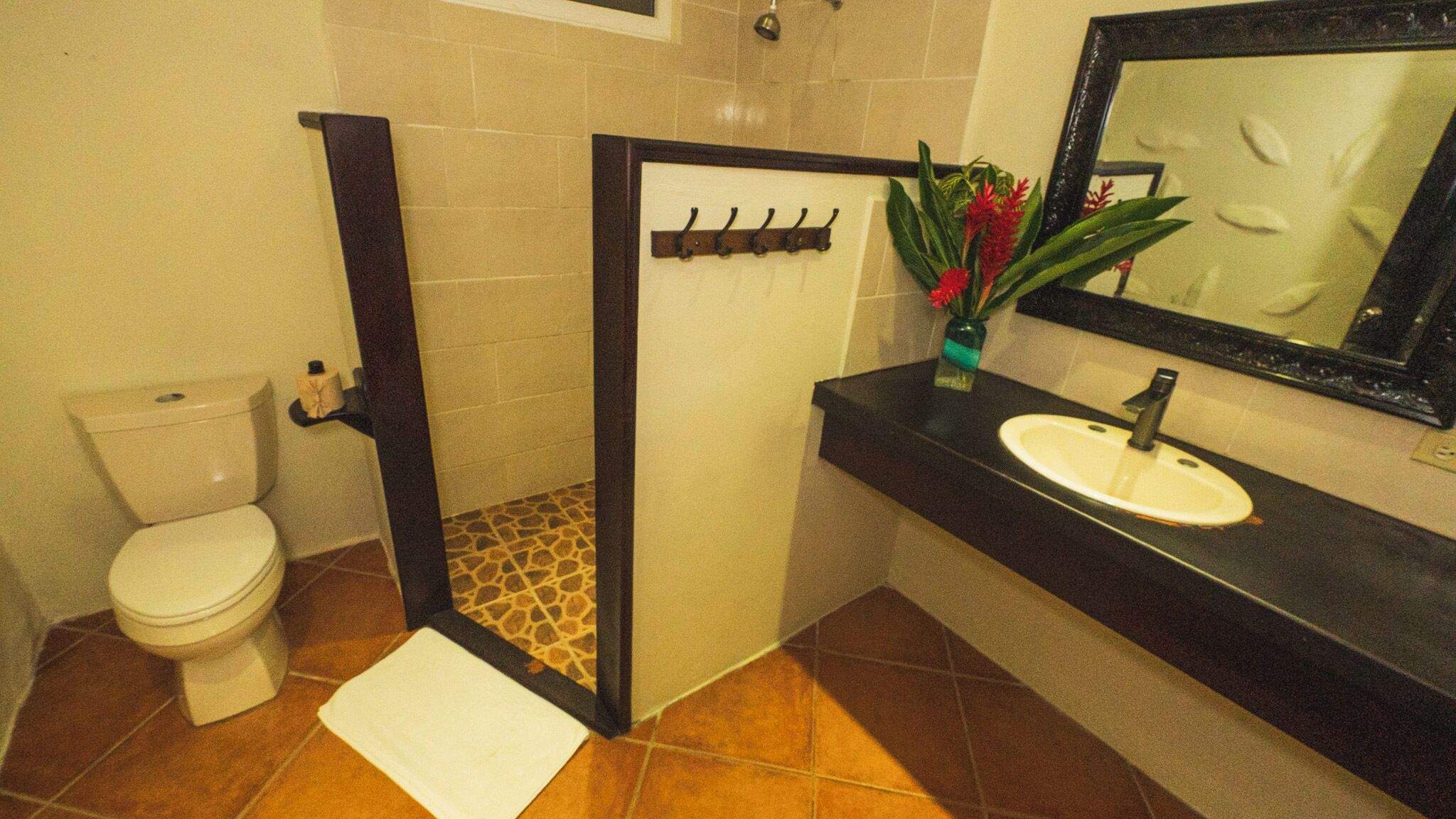 Un baño con inodoro, lavamanos, espejo y zona de ducha.