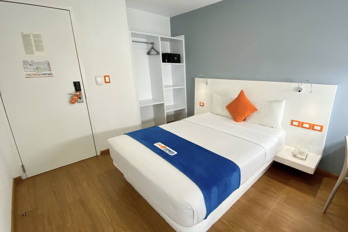 A hotel room with a bed, a desk, and a chair.