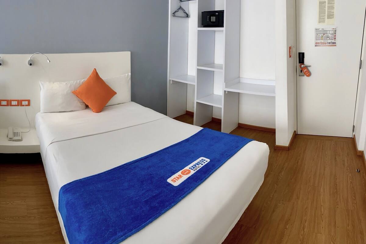 A hotel room with two beds, a desk, and a shower area.