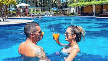 Una piscina al aire libre, sombrillas, sillones reclinables de piscina