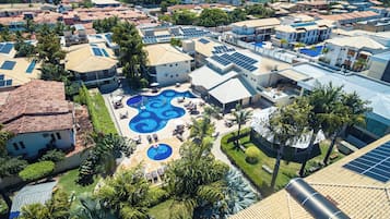 An aerial view of a residential area with multiple houses, a swimming pool, and solar panels on rooftops.