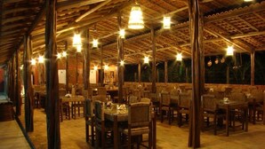 Un espace de restauration intérieur avec des tables et des chaises en bois, un sol en briques et des luminaires suspendus.