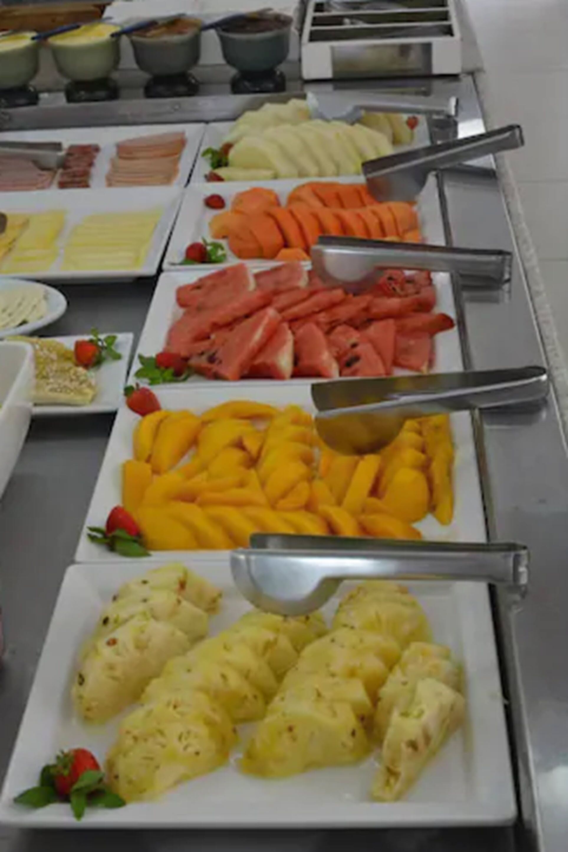 Un bufé con diversas opciones de comida, incluyendo frutas, quesos y embutidos.