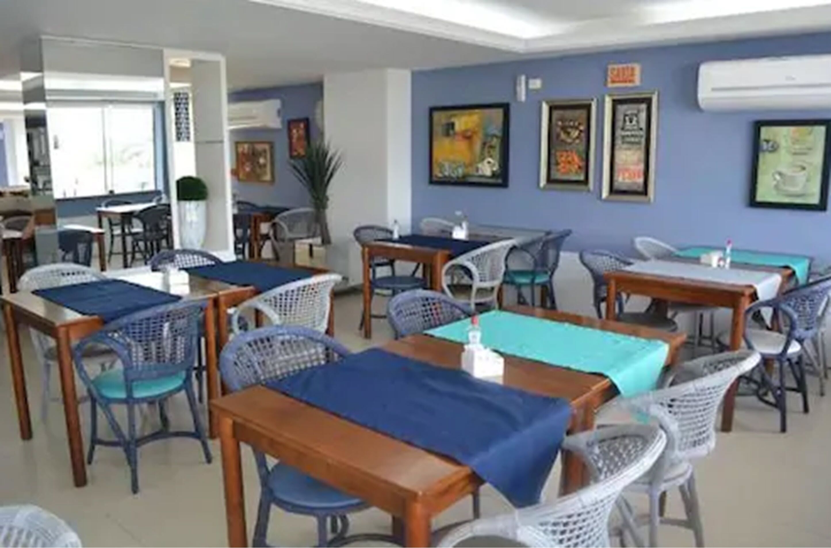 A dining area with multiple tables and chairs, some covered with blue tablecloths.