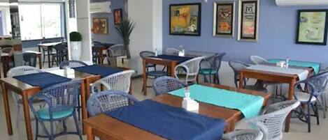 A dining area with multiple tables and chairs, some covered with blue tablecloths.