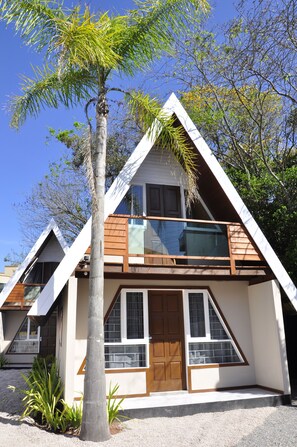 A two-story house with a balcony, a wooden door, and a window with a view of the sky.